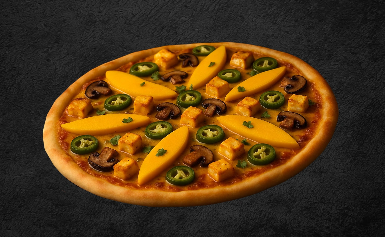 Fusion pizza topped with fresh mango slices, paneer cubes, jalapeño peppers, mushrooms, and herbs on a dark background.
