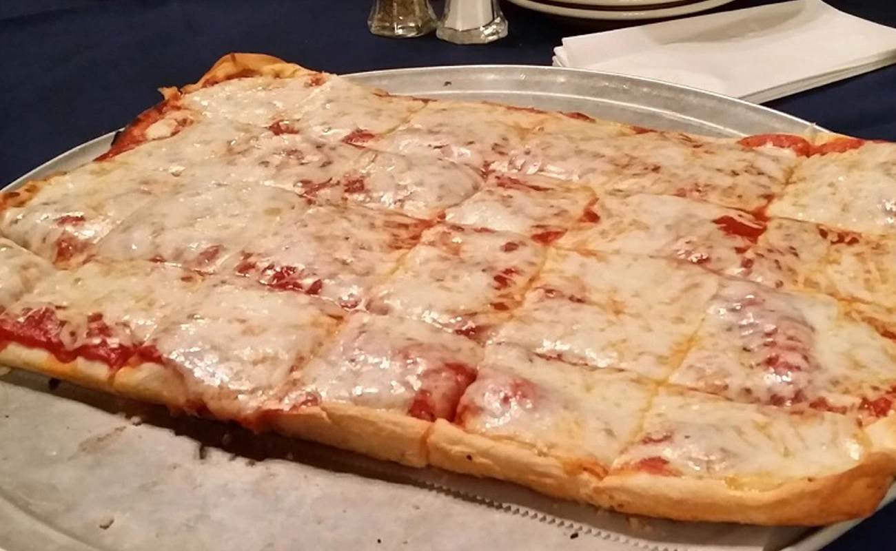 Old Forge-style pizza served on a rectangular tray, topped with a blend of cheeses and cut into square slices.