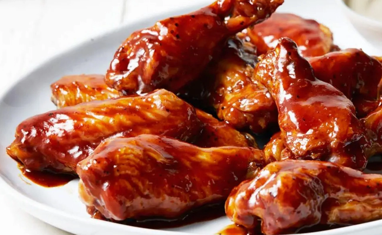 Close-up of classic BBQ glazed wings served on a white plate.
