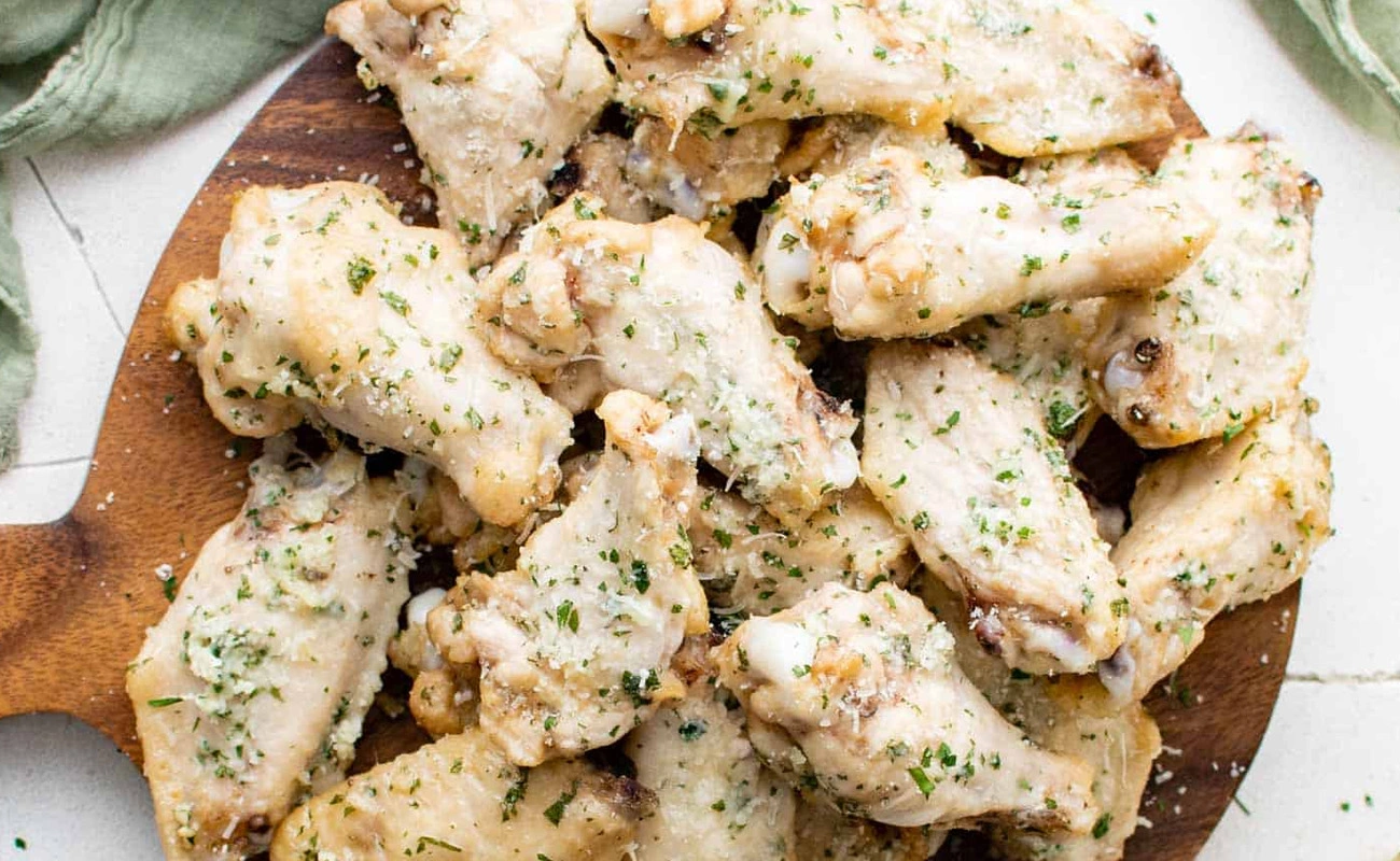 Garlic parmesan chicken wings tossed in creamy sauce and fresh herbs – crispy baked wings full of flavor