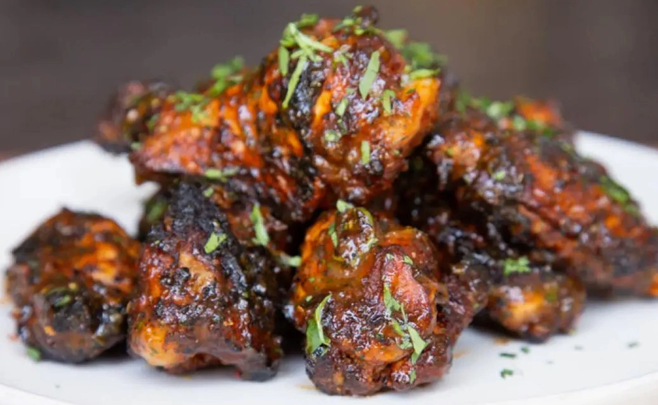 Close-up of golden wings and chili pepper, representing the heat of Jamaican Jerk Sauce.