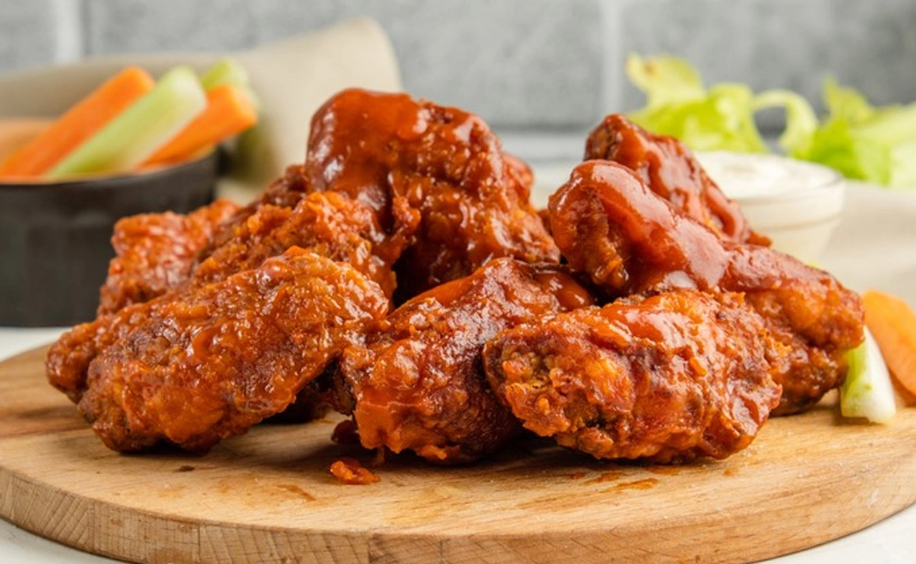 Spicy buffalo chicken wings served with dipping sauce and fresh veggie sticks – crispy fried wings coated in tangy hot sauce.